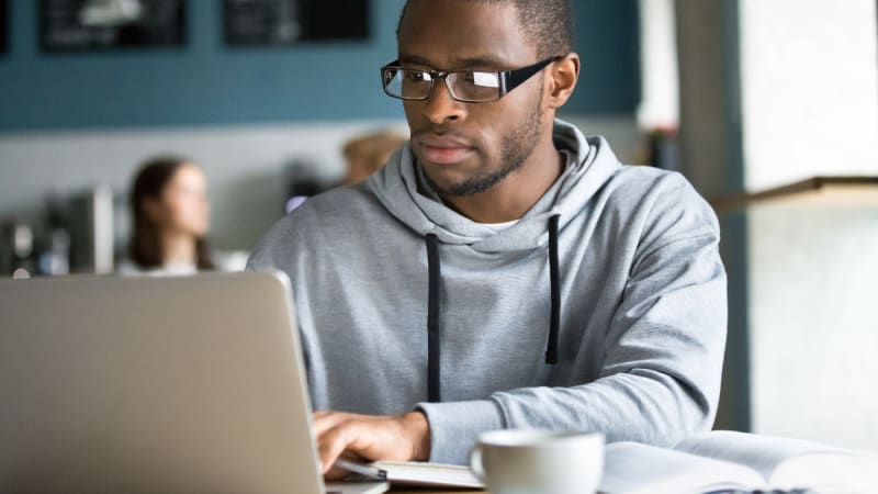 Male student studying on laptop