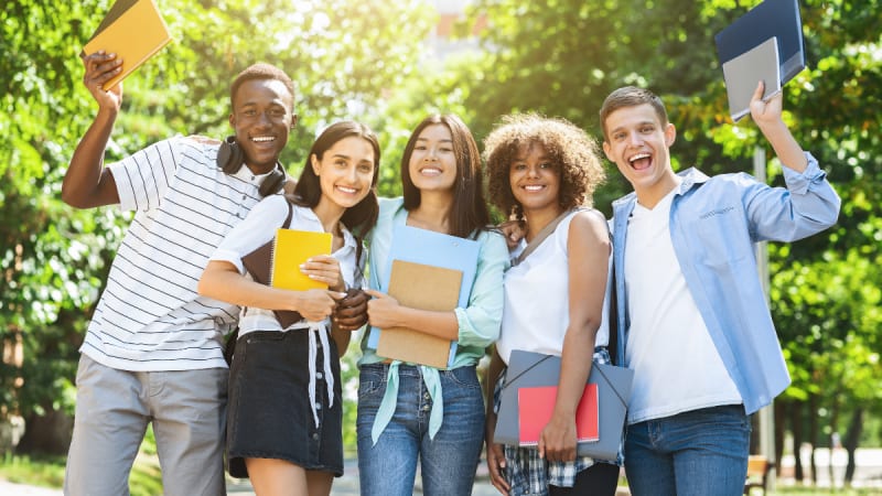 Students smiling and waving outside