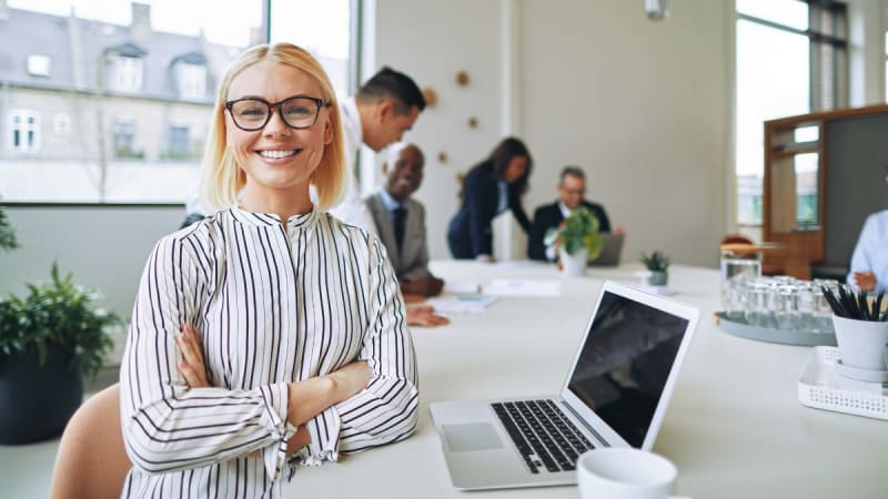 Woman sitting down smiling next to a laptop