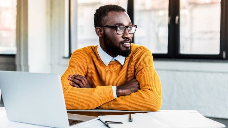 Man thinking next to a laptop