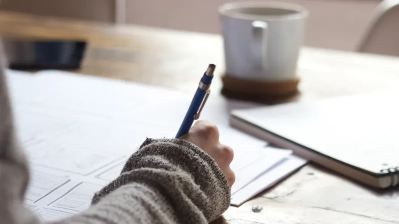 Hands writing at a desk