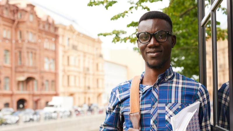 Male student standing near an empty street