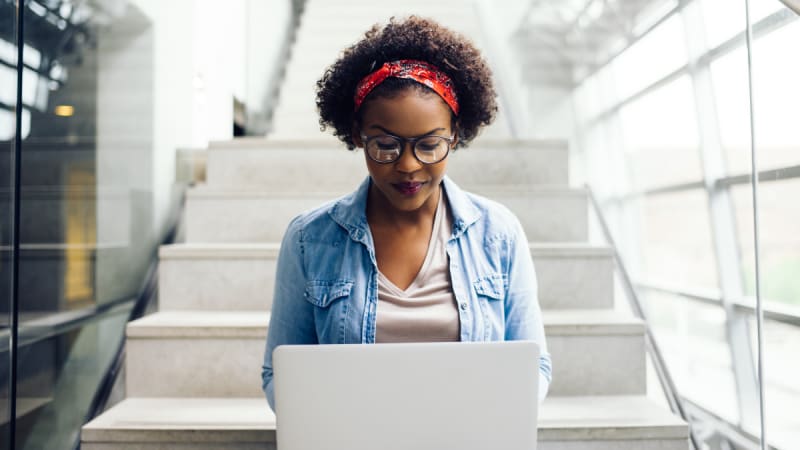 Woman working at the bottom of steps on a laptop