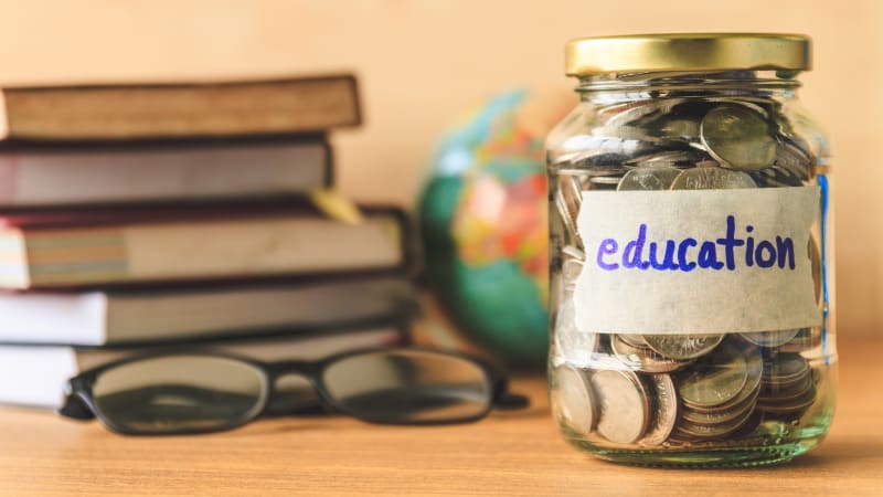 Jar of money next to textbooks