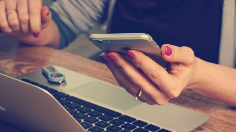 Person using a phone and laptop