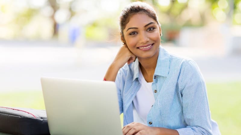 Student sitting outside working on an online lesson for college