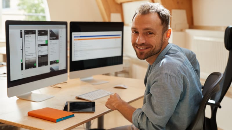 cybersecurity professional sitting at a desk in front of two computers