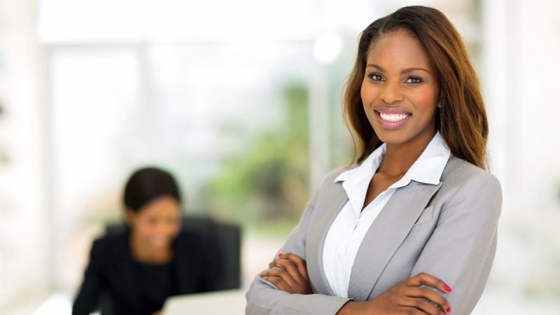 MBA graduate standing in an office setting smiling at the camera